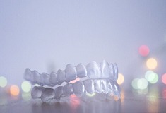 Invisalign clear aligners in front of backdrop.