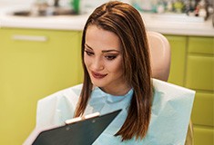 Woman in dental chair looking at patient chart
