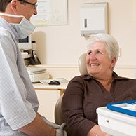 Older woman in dental chair talking to her dentist