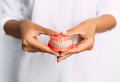 Close-up of hands holding dentures in Forest, VA