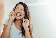 woman brushing teeth in bathroom mirror