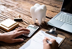 Patient filling out dental insurance paperwork and using calculator