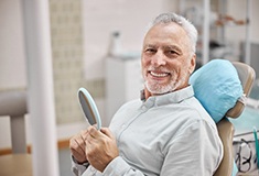 Closeup of man smiling while holding small mirror