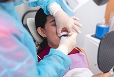 Dentist placing trays of fluoride over patient’s teeth