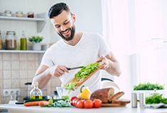 Smiling man preparing salad at home