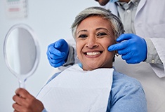 Woman smiling while holding handheld mirror