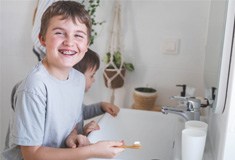 young boy with braces brushing teeth 