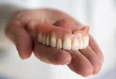 Close up of person holding denture