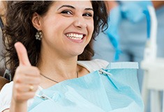 Woman in dental chair giving thumbs up