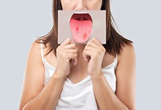 Patient holding up illustration of oral cancer on tongue