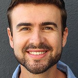 Man with beard and light blue shirt smiling