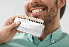 man smiling while dentist color matches veneers in Forest