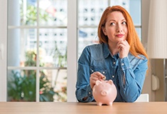 Woman putting a coin into a piggy bank