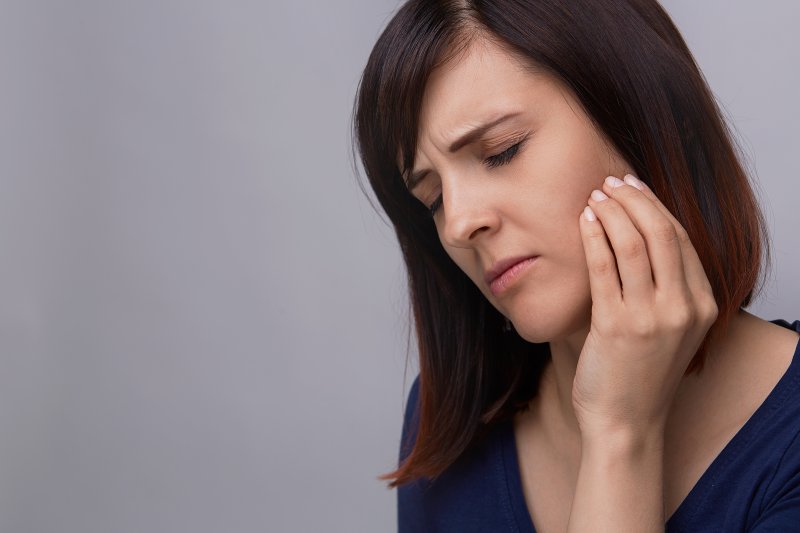 a woman holding cheek in pain