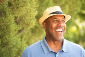 man in blue shirt and fedora standing among trees
