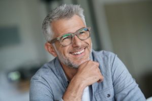 smiling gray-haired man happy about the cosmetic benefits of dental implants 