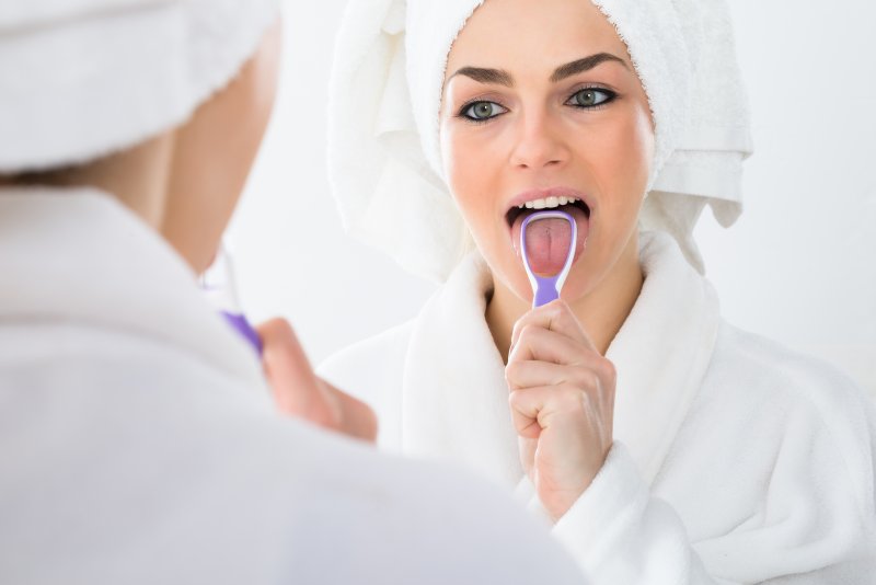 woman cleaning her tongue with tongue scraper